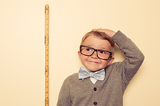 Boy with glasses measuring his height with a yard stick.