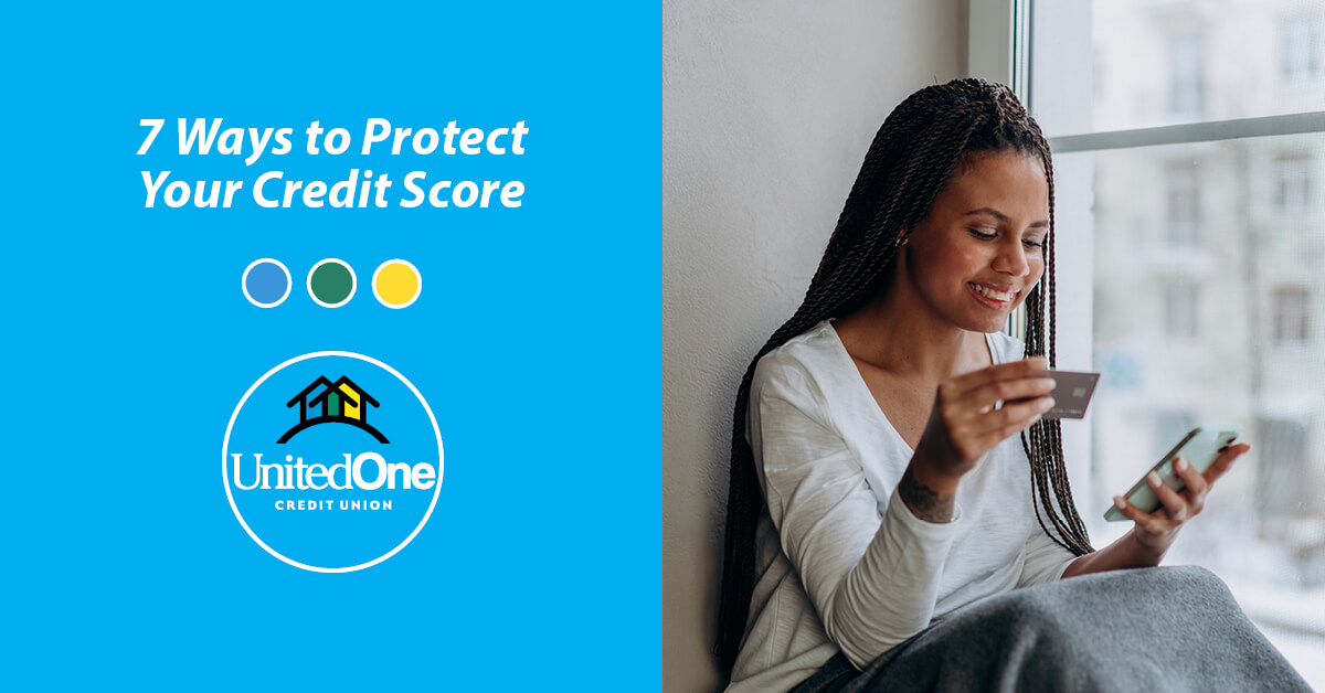 A woman smiling while sitting and looking at a laptop and holding a credit card