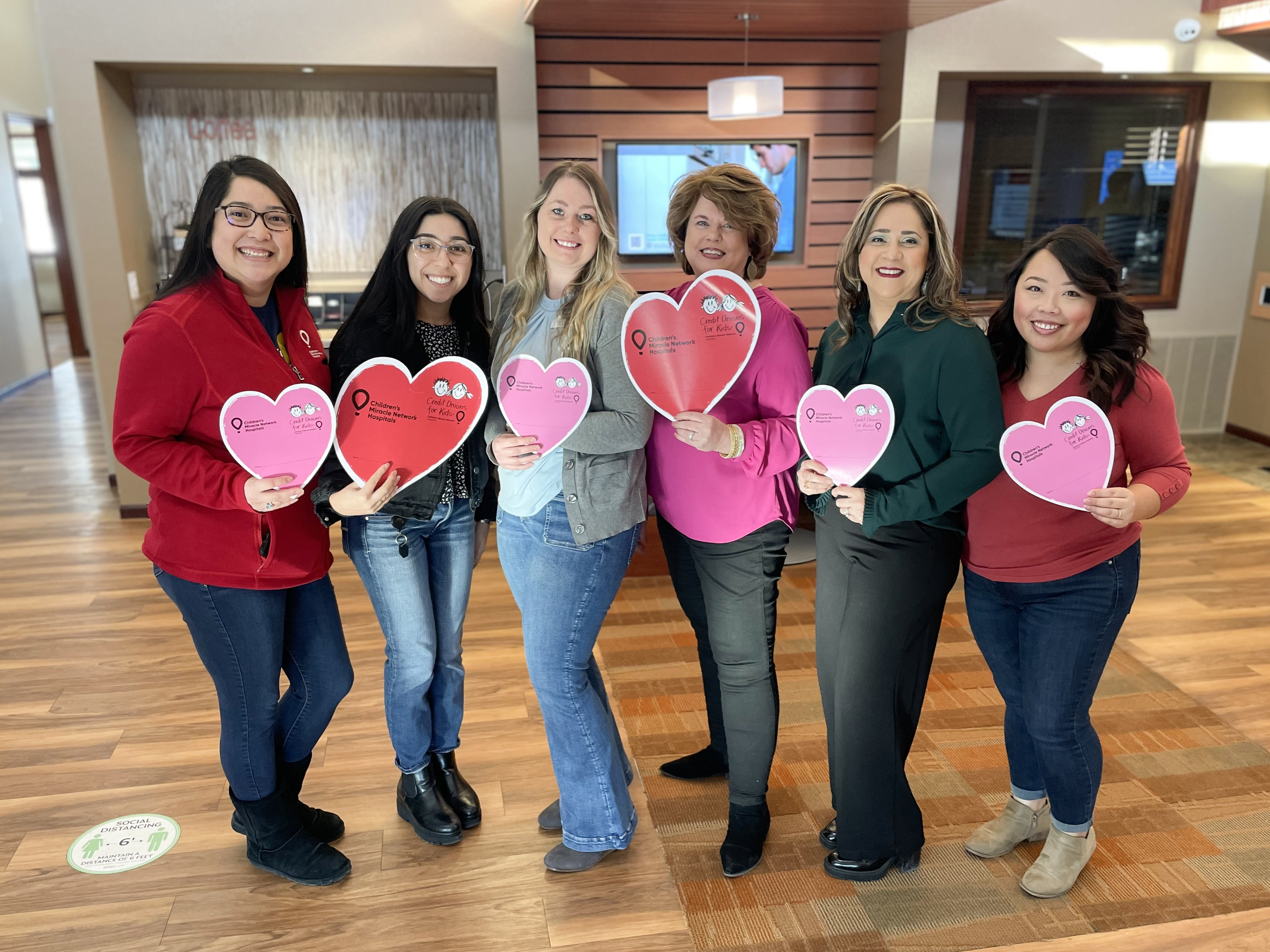 A group of UnitedOne CU staff holding hearts in support of Children's Wisconsin