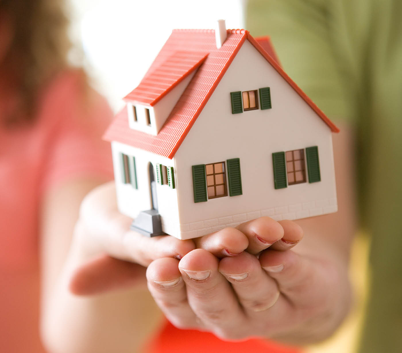 Two hands holding a model house together