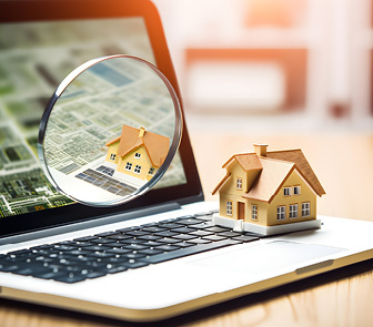 Model house next to a magnifying glass and laptop