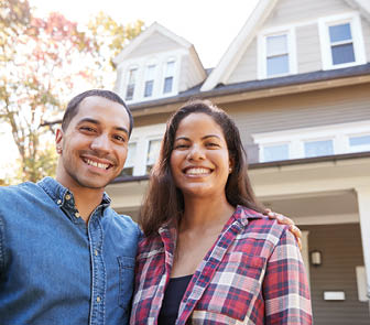 Husband and wife standing in front of home