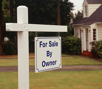 For sale sign posted in front of house