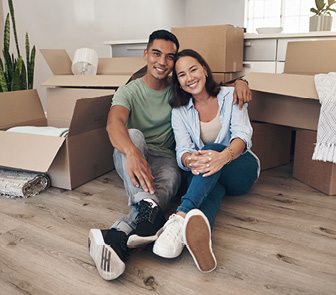 Couple sitting on the floor with moving boxes in the background