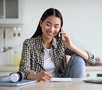 Woman talking on the phone and writing on a piece of paper