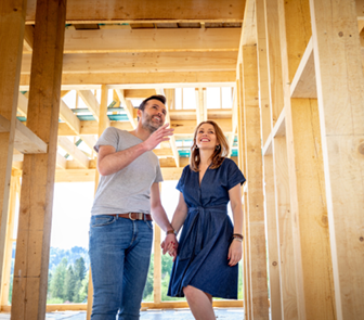 Young couple walking through framing of a new home being built
