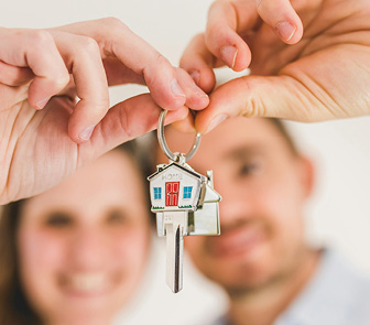 Two people holding a set of house keys together